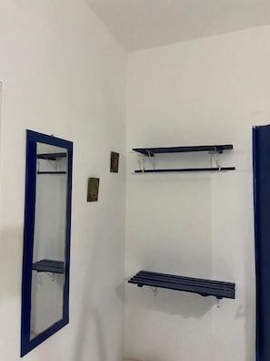 A bathroom with a mirror and three shelves.