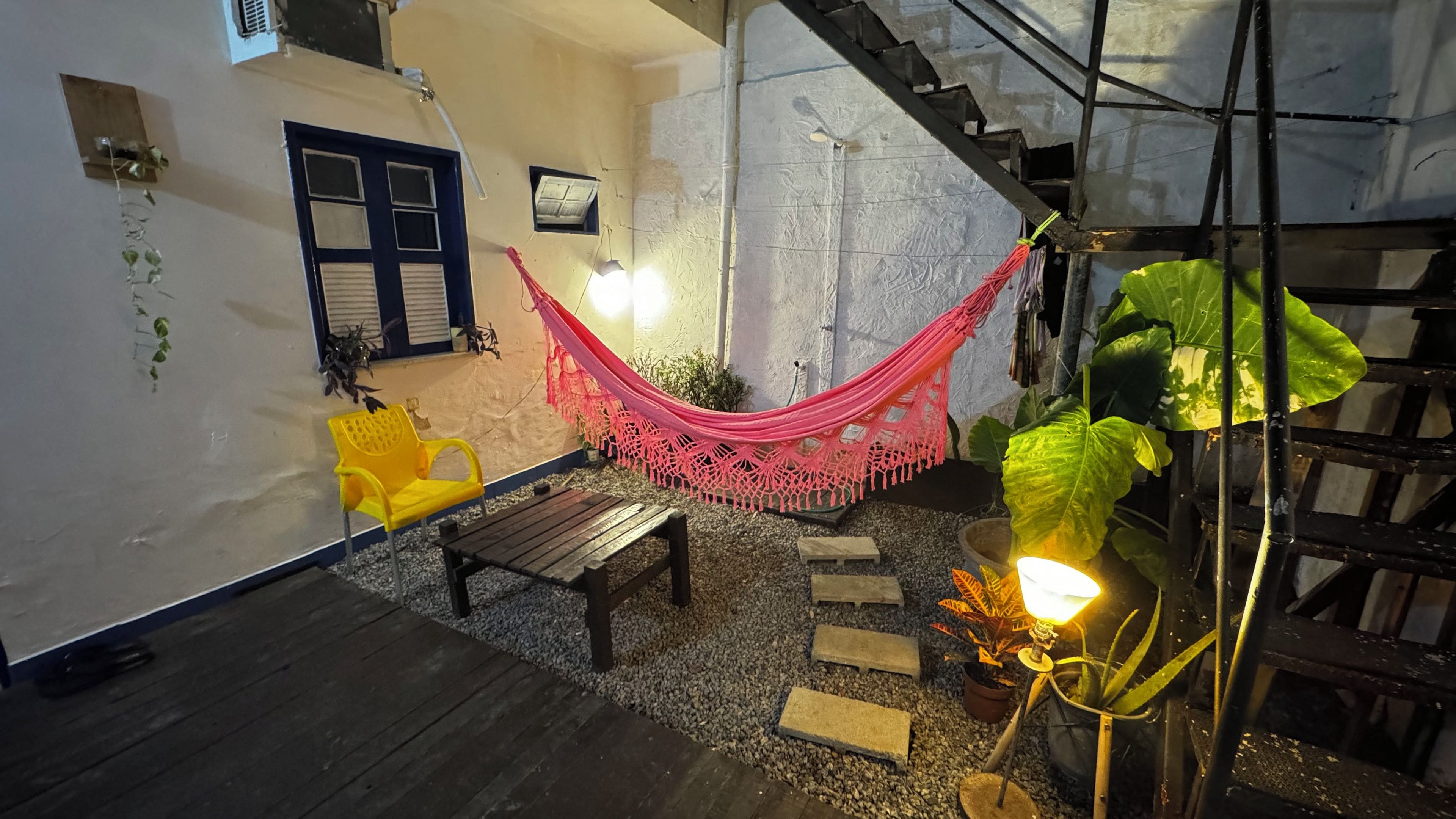 A cozy outdoor seating area with a hammock, wooden furniture, and potted plants.