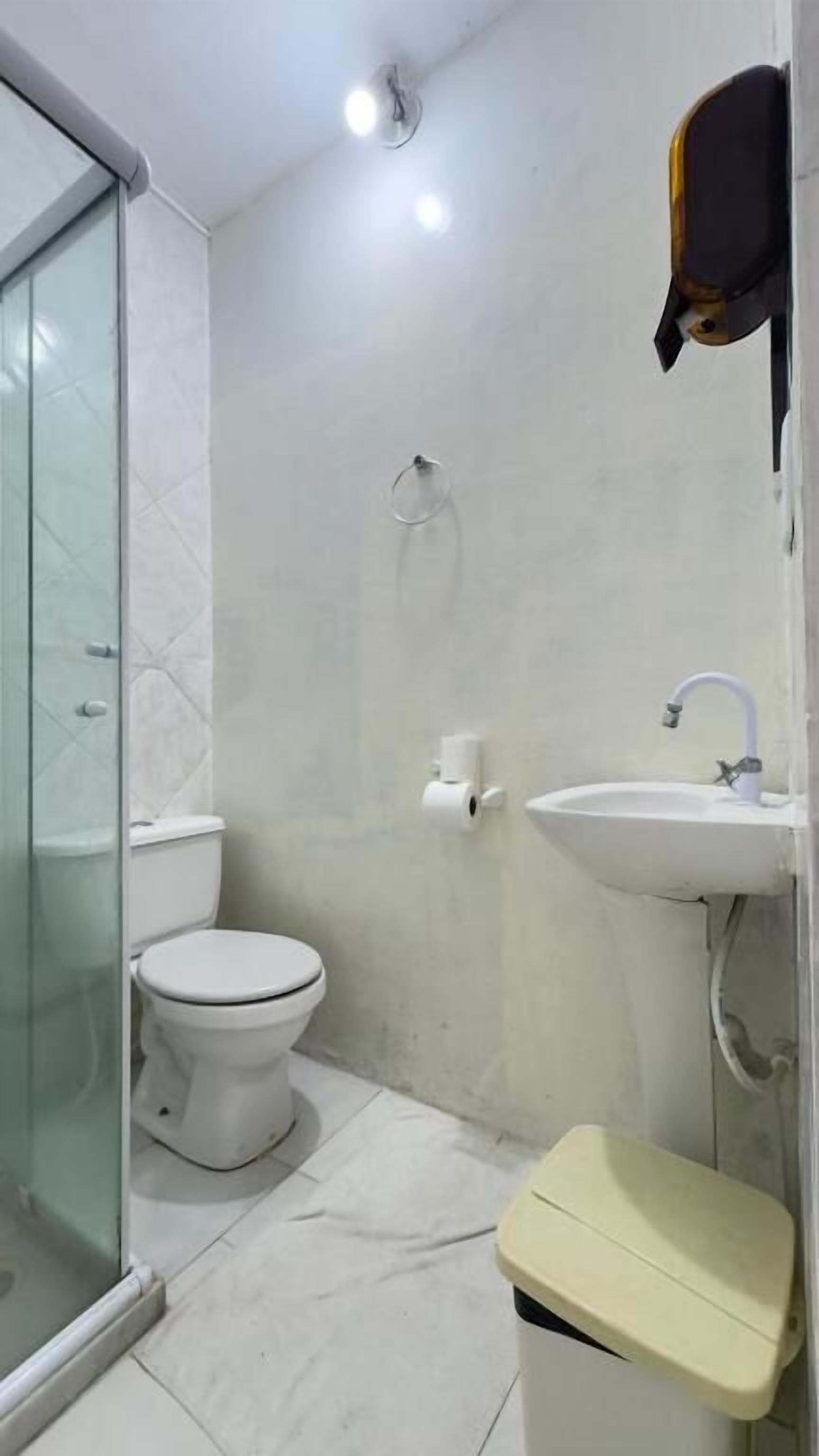Casa de banho com sanita, lavatório e chuveiro.