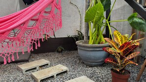 A garden area with a hammock, potted plants, and stepping stones.