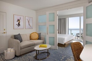 Ein Hotelzimmer mit Sofa, kleinem runden Tisch, Bett und Meerblick.