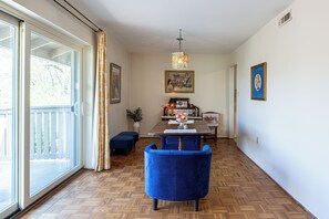 A dining area with a wooden herringbone floor, a blue upholstered chair, a dining table with a vase of flowers, and a chandelier. - Large 2 Bed 2 Bath Condo in Prime West Knoxville/Bearden/Sequoyah Hills (Knoxville)