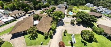 Vista aérea de uma área residencial com várias casas, piscina e áreas verdes.