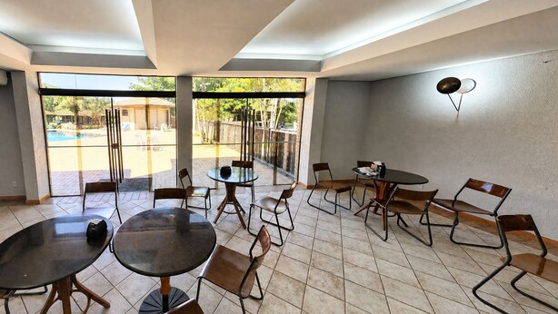 A dining area with tables and chairs, a water dispenser, and a microwave on a counter.