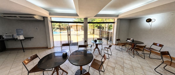 A dining area with tables and chairs, a water dispenser, and a microwave on a counter.