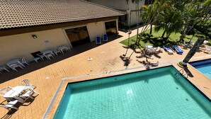 A rooftop pool area with two pools, lounge chairs, and a covered seating area.
