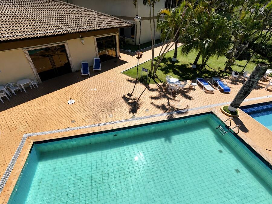A rooftop pool area with two pools, lounge chairs, and a covered seating area.