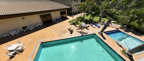 A rooftop pool area with two pools, lounge chairs, and a covered seating area.