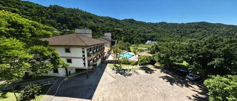 A hotel with a pool, surrounded by lush greenery and hills.