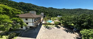 Un hotel con piscina, rodeado de exuberante vegetación y colinas.