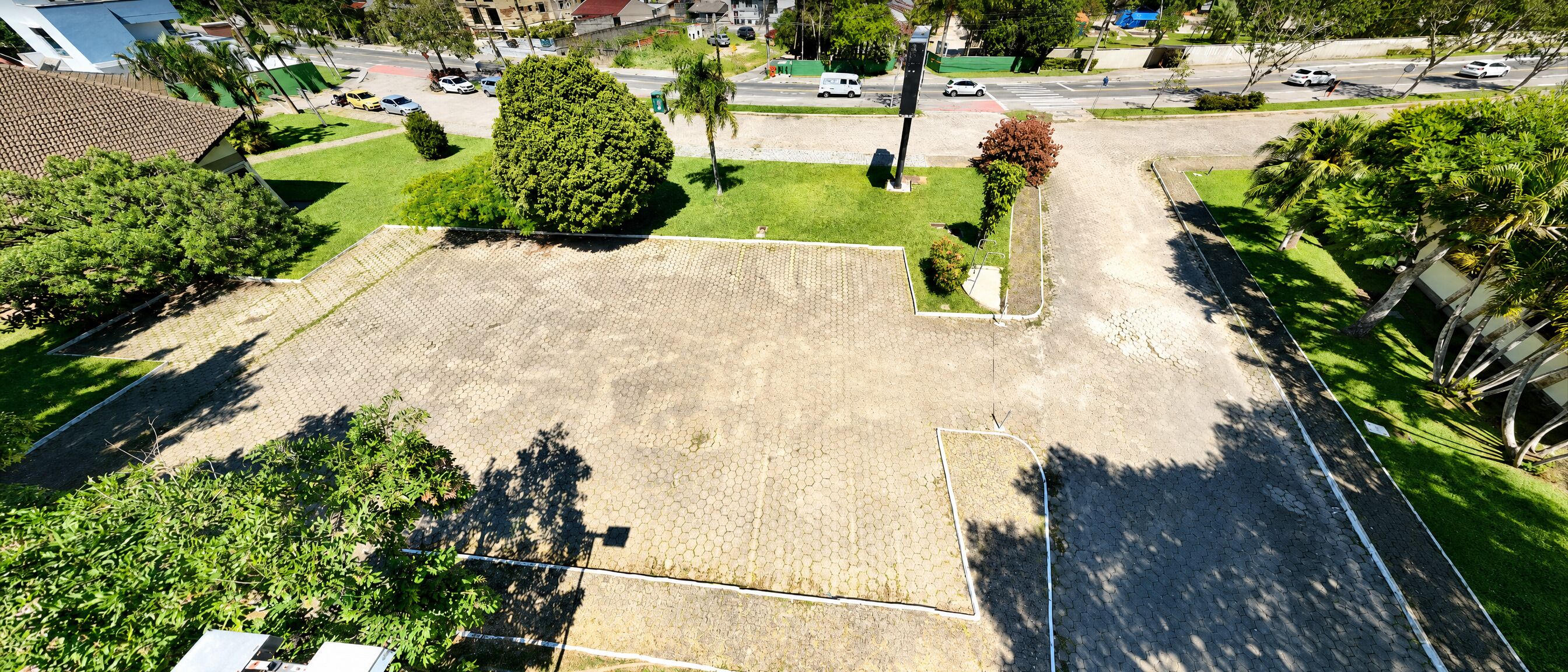 Vista aérea de un barrio residencial con un amplio espacio abierto, posiblemente un parque o patio, rodeado de casas y vegetación.