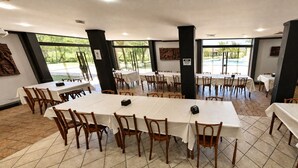 A dining area with multiple tables and chairs, large windows, and a view of an outdoor swimming pool.