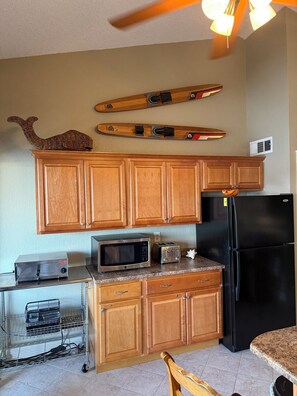 A kitchen with wooden cabinets, a microwave, toaster, and a black refrigerator. - Heron Bay 2B 2B condo vaulted ceiling next to pool pwc boat slip available (Osage Beach)