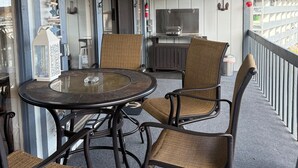 Ein überdachter Außenbereich mit rundem Tisch und vier Stühlen, Deckenventilator und Blick auf die Stadt.