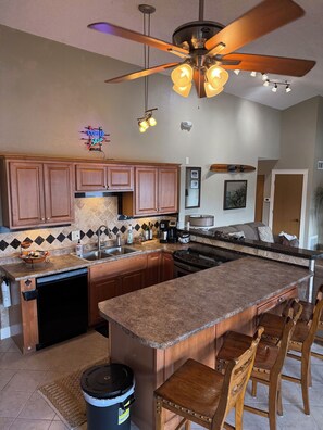 A kitchen with a central island, wooden cabinets, a dishwasher, and a ceiling fan. - Heron Bay 2B 2B condo vaulted ceiling next to pool pwc boat slip available (Osage Beach)