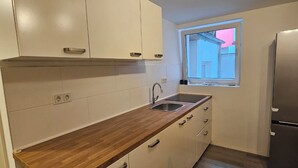 Una cocina moderna con armarios blancos, encimera de madera, pileta de acero inoxidable y refrigerador empotrado.