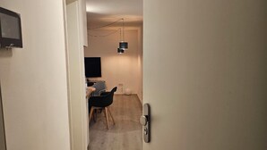 Un pasillo que conduce a una habitación con escritorio, silla y televisor.