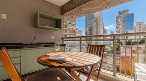 Ein Balkon mit Esstisch, Stühlen, einem Weinglas und einem Teller.