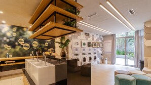Una bugaderia moderna amb diverses rentadores, una zona de piques i una sala d'estar amb otomans.