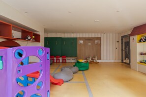 Zona de juegos infantiles con estructuras coloridas, asientos y una canasta de baloncesto.