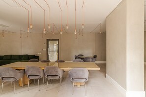 A modern meeting room with a long table, six chairs, and pendant lighting. - Studio com Varanda perto do Metrô em Pinheiros (São Paulo)