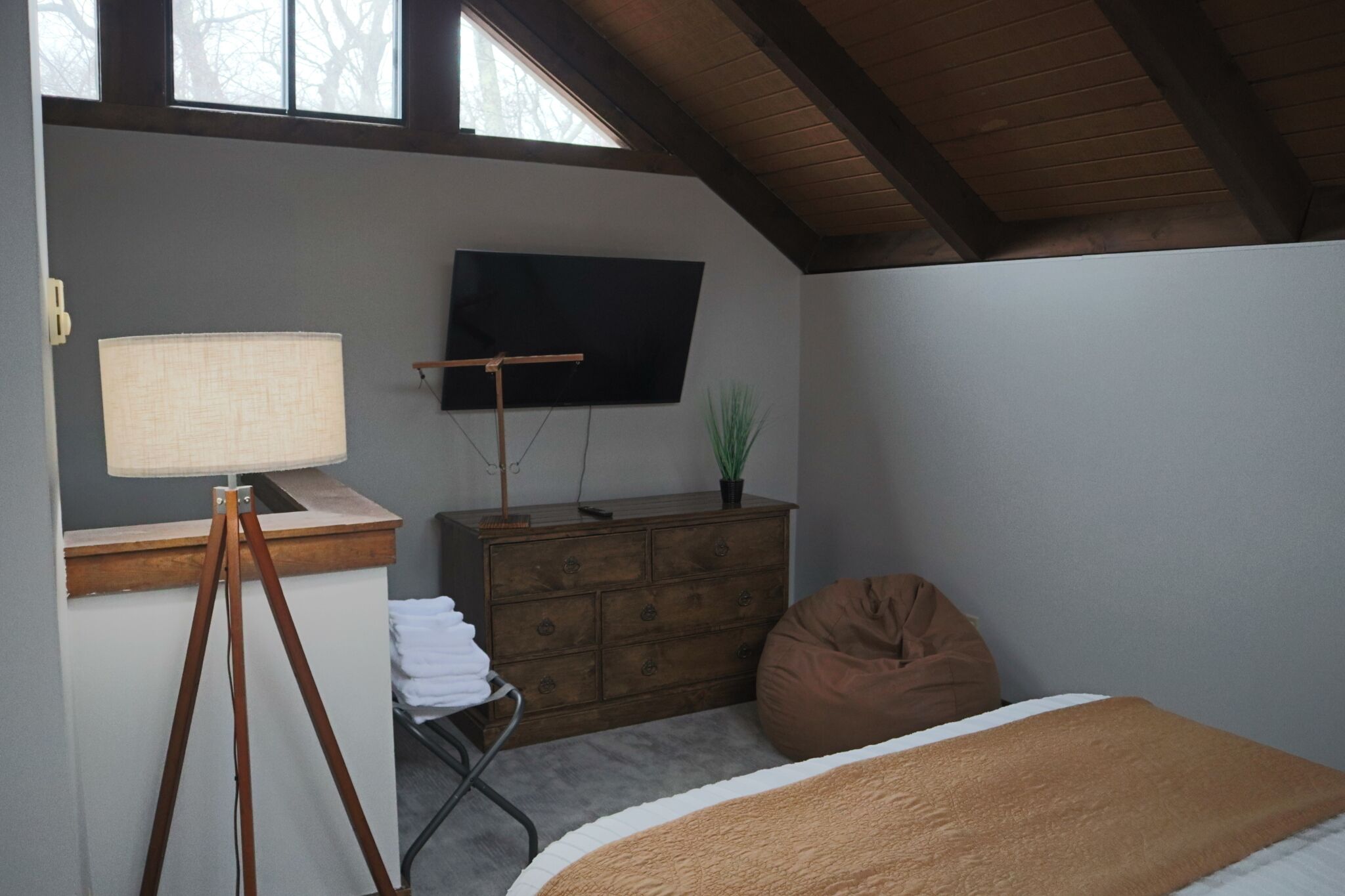 Ein Schlafzimmer mit einem Bett, einem Schminktisch, einem Fernseher, einer Lampe und einem Fenster.