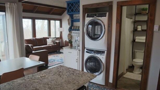 Un espace de vie compact comprenant un coin cuisine, une table à manger, un canapé et un espace buanderie avec un lave-linge et un sèche-linge.