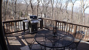 Une terrasse extérieure avec un barbecue, une table en métal et des chaises.