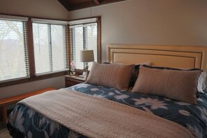 A bedroom with a bed, a nightstand, a lamp, and a window with blinds. - Ski in Style @ Sapphire Squirrel (Wintergreen Resort)