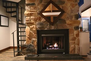 A stone fireplace with a modern design, a black metal staircase, and a framed picture on the wall. - Ski in Style @ Sapphire Squirrel (Wintergreen Resort)