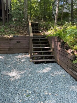 A wooden staircase with a metal railing leading up to a building, surrounded by trees and gravel. - Ski in Style @ Sapphire Squirrel (Wintergreen Resort)