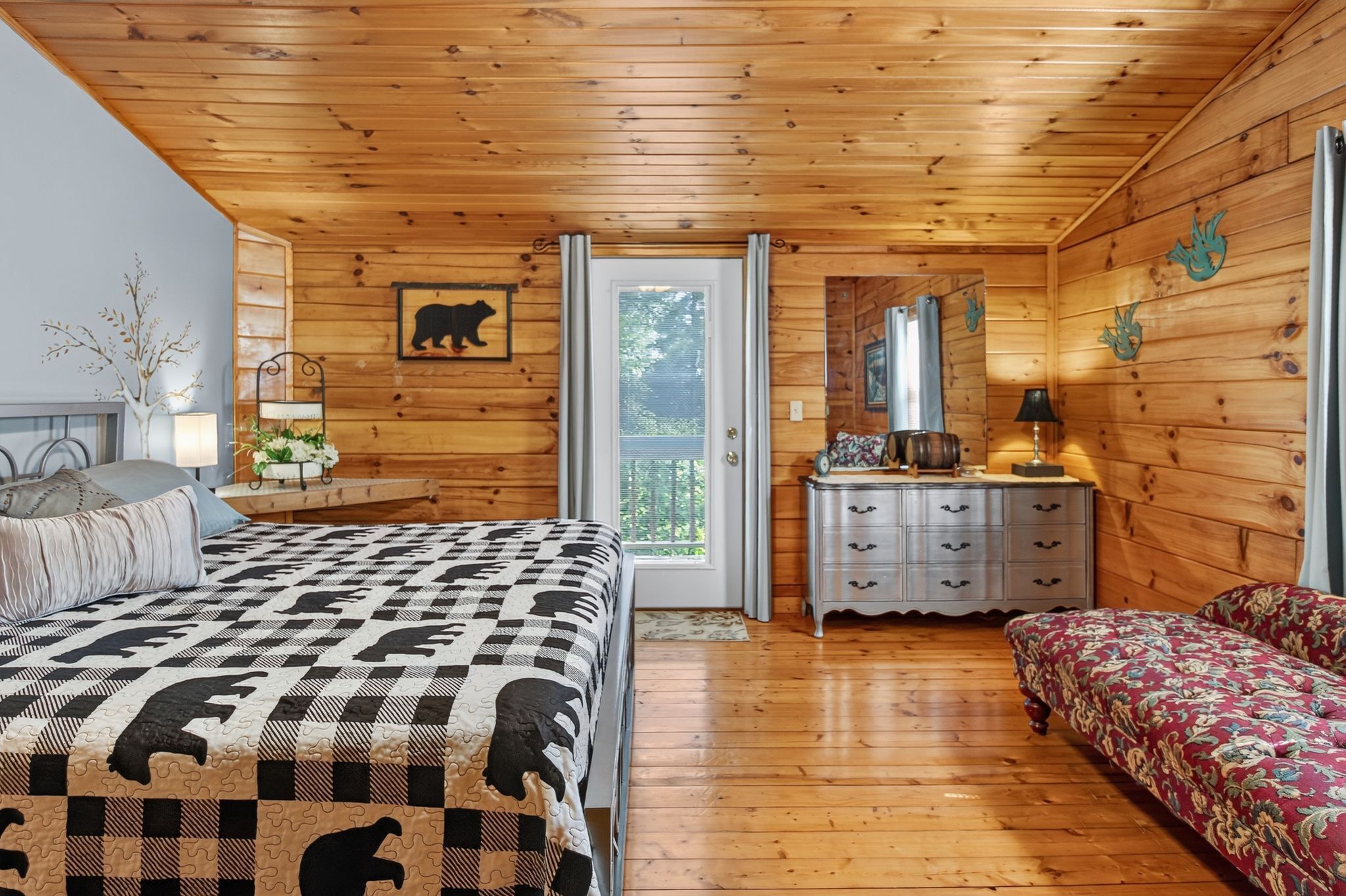 A wooden cabin bedroom with a bed, dresser, and a bench.