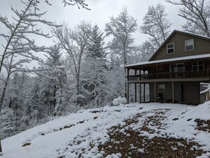 A two-story wooden cabin with a balcony, surrounded by snow-covered trees. - Secluded Cabin Near Whitewater Rafting + Hiking! (Hartford)