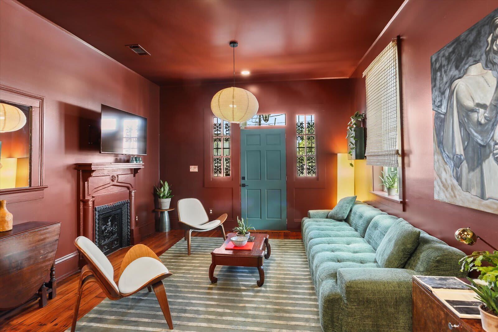 A cozy living room with a fireplace, a sofa, a television, and a painting on the wall.