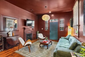 A living room with a fireplace, a sofa, a television, and a door with decorative glass panels.