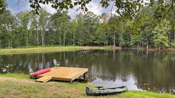 Un cadre paisible au bord d’un lac, avec un quai en bois, un canoë et une chaise.