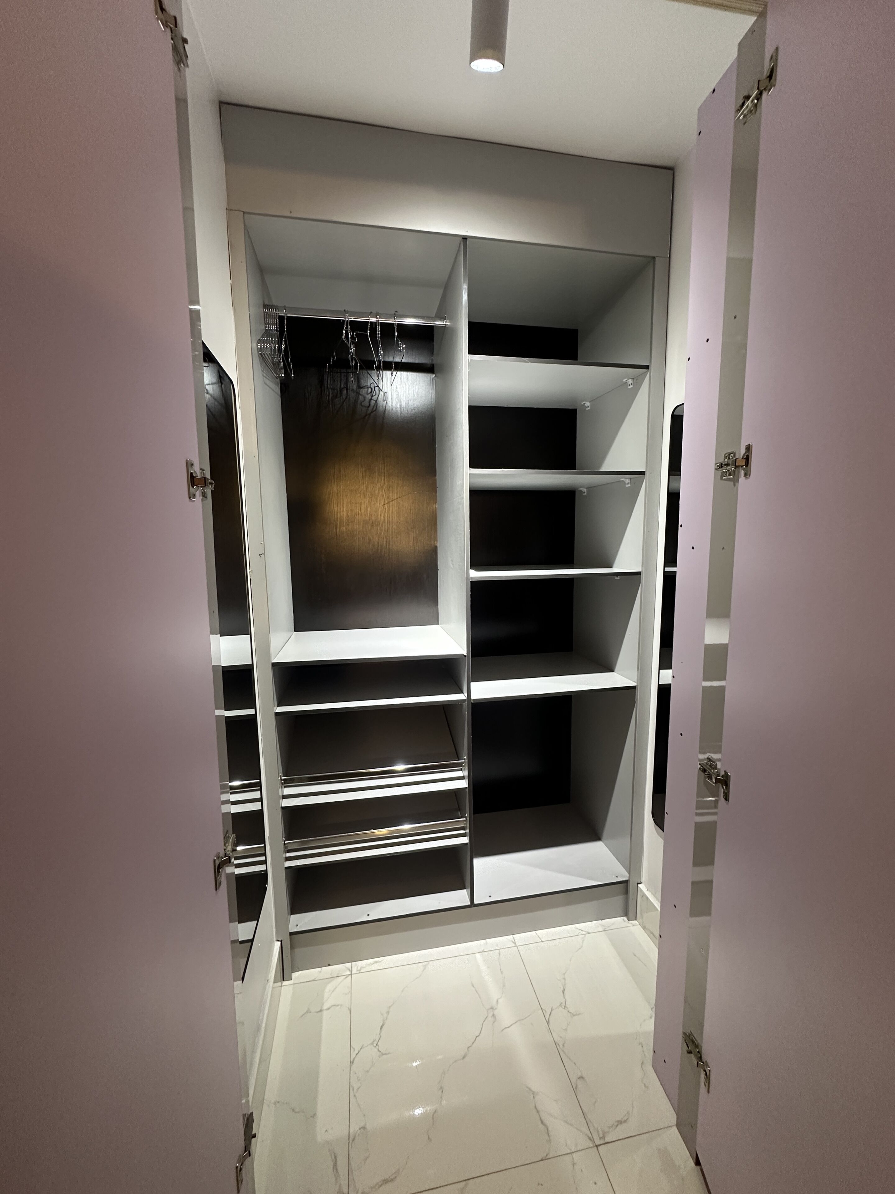 A walk-in closet with open doors, revealing shelves and hanging space.