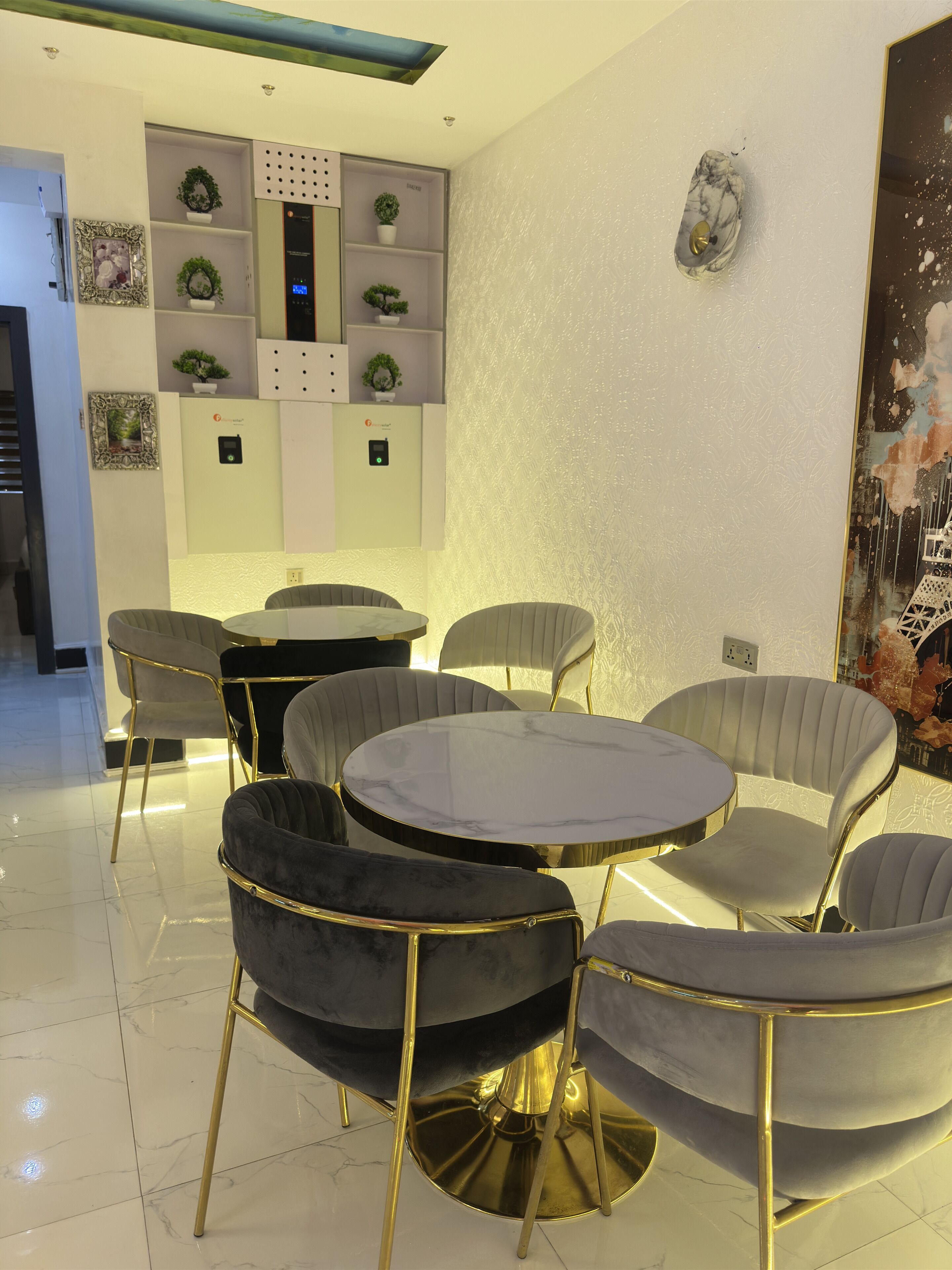 Een moderne eetruimte met een ronde tafel en zes stoelen, een bedieningspaneel aan de muur en decoratieve wandkunst.