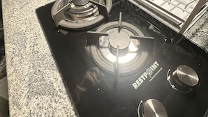 Una cocina con estufa a gas, un lavamanos y un escurreplatos.