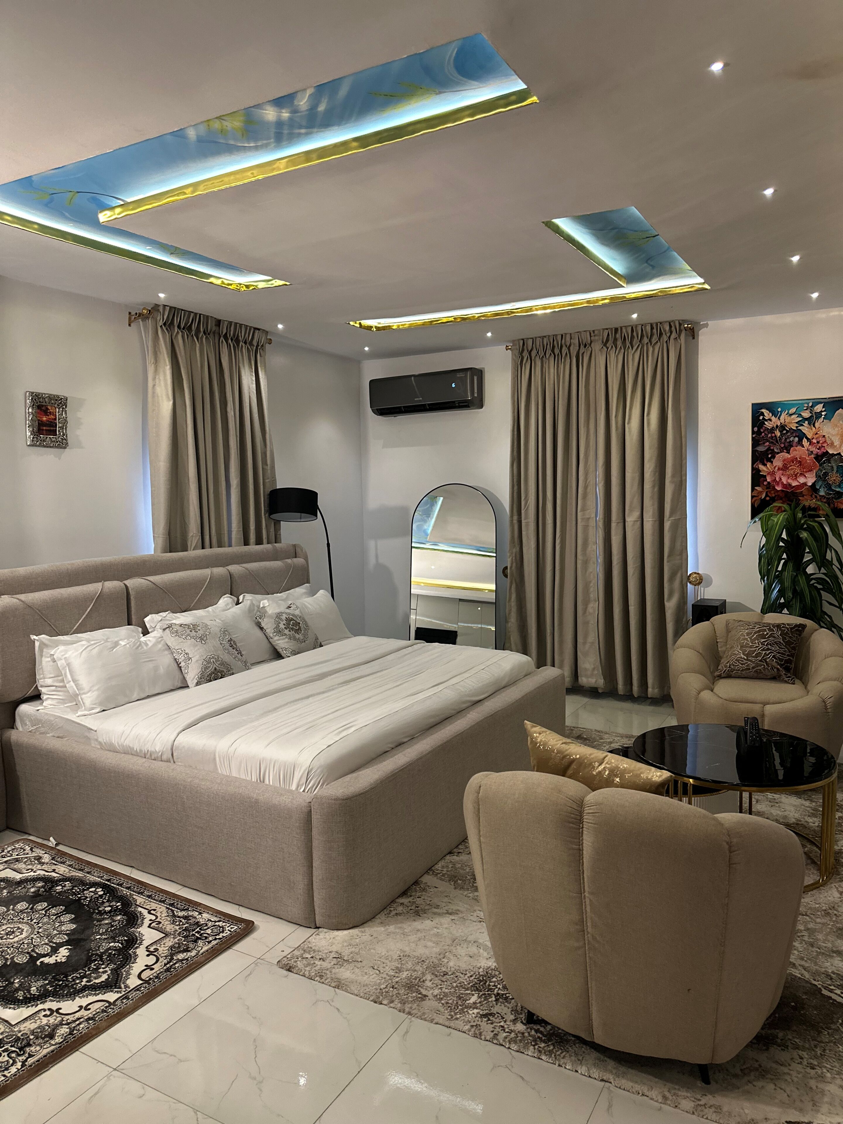 A modern bedroom with a large bed, a sofa, a coffee table, and a mirror.