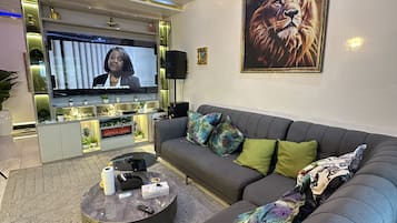 Een moderne woonkamer met een grijze bank, een salontafel en een televisie.