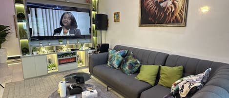 Una sala de estar moderna con un sofá gris, una mesa de centro y un televisor.