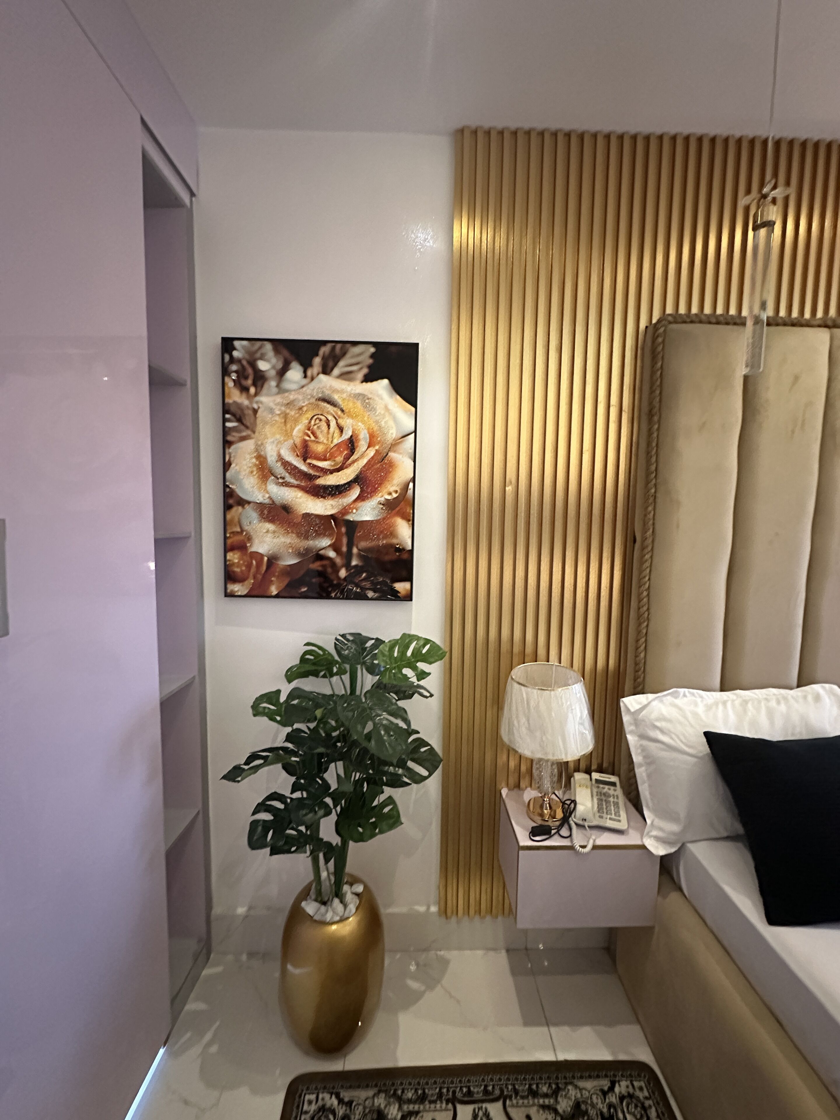 Een moderne hotelkamer met een groot bed, een nachtkastje met een lamp, een telefoon en een decoratieve plant.