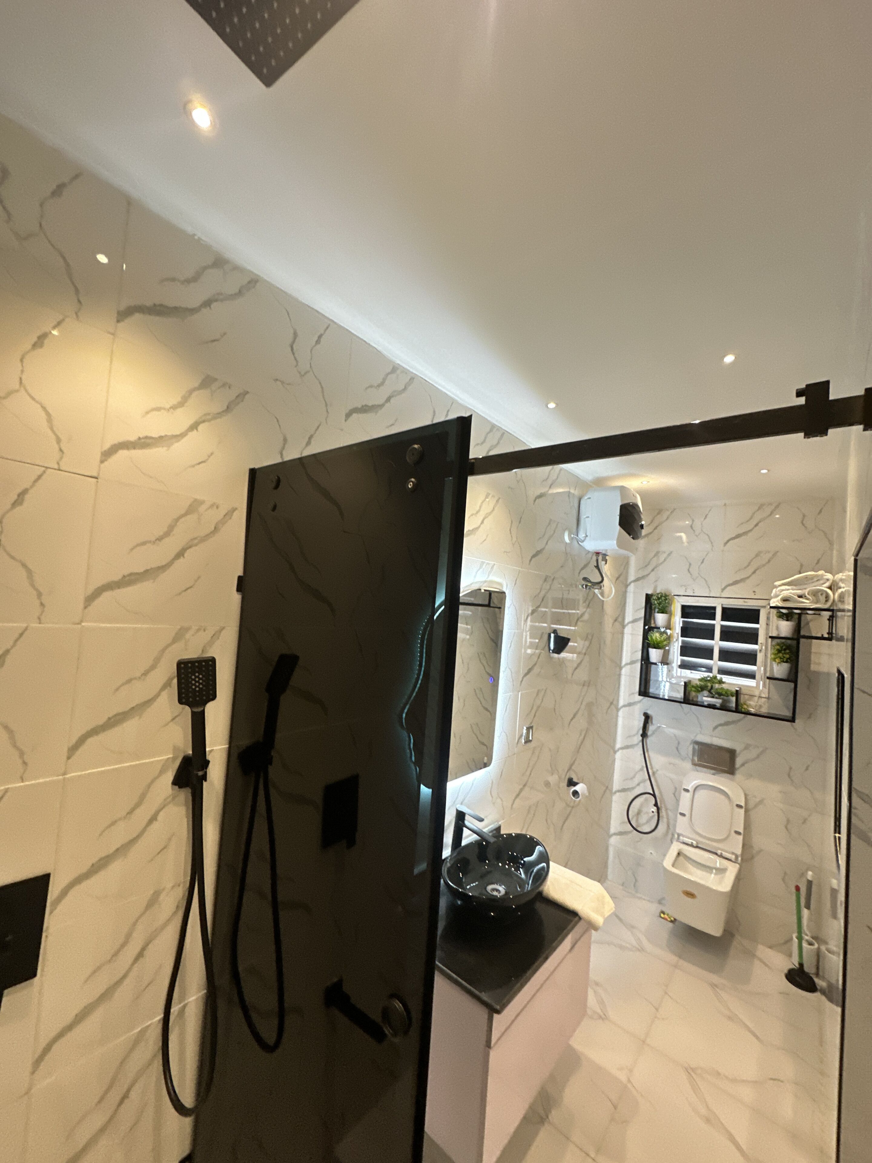 Un baño moderno con cabina de ducha de vidrio, inodoro y lavamanos.