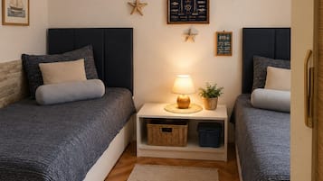 Quarto com duas camas, uma mesa de cabeceira com abajur, decoração com estrelas e um mapa náutico emoldurado.