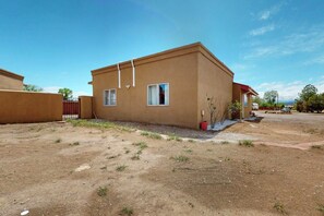 A single-story building with a flat roof, a small porch, and a gated entrance. - Entire Desert Hacienda Estate Compound - Sleeps 12 in La Mesilla, New Mexico (Española)