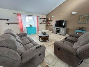 A living room with two grey sofas, a TV stand, and a coffee table.