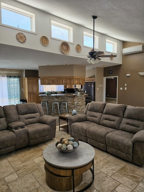 A spacious living room with two sofas, a coffee table, and a kitchen in the background.