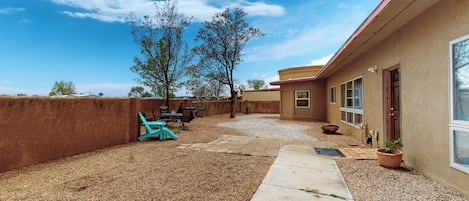 Patio trasero residencial con área de estar y un ventanal grande.