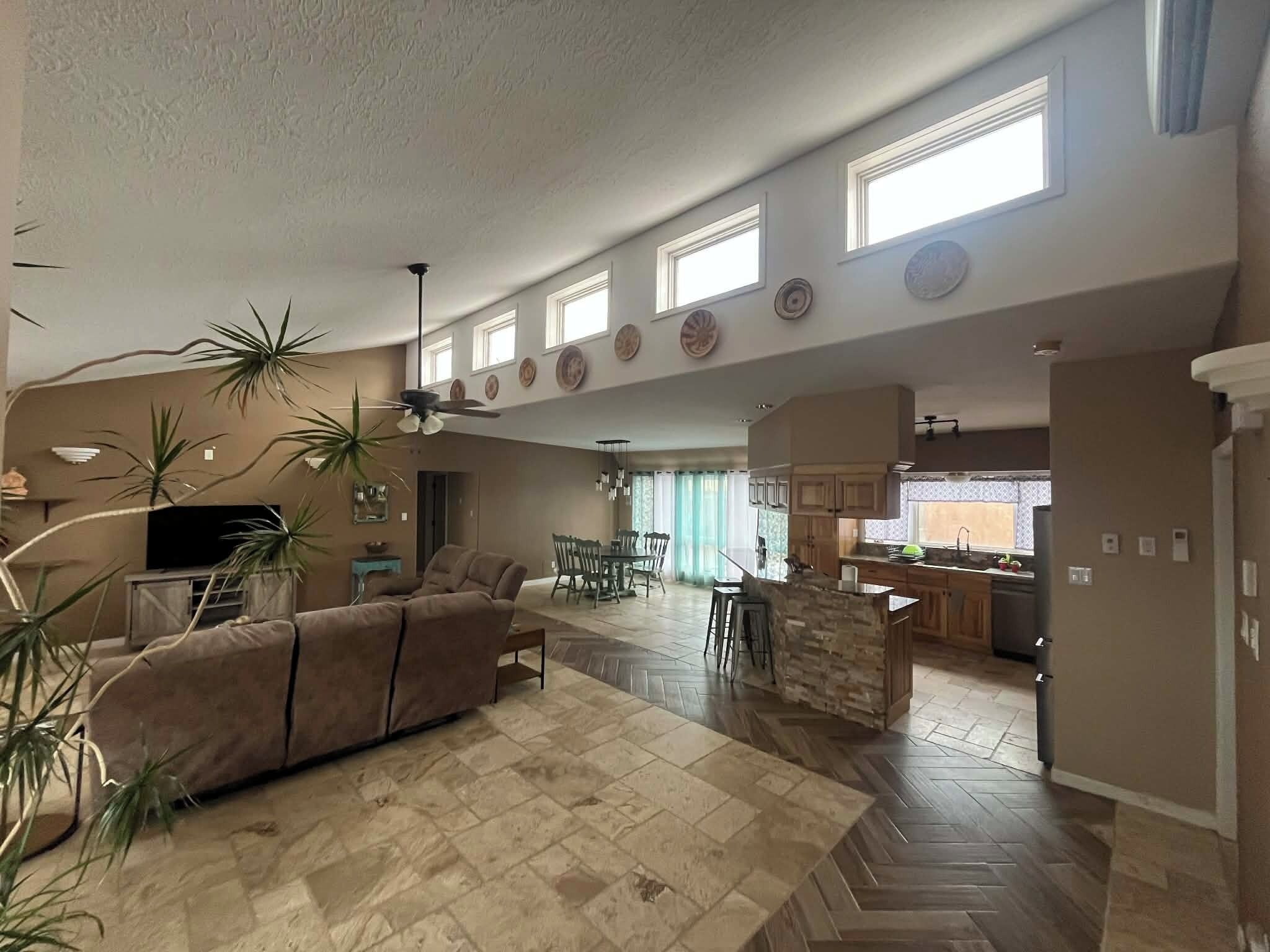 Amplia sala de estar con un sofá grande, una mesa de comedor y una cocina al fondo.